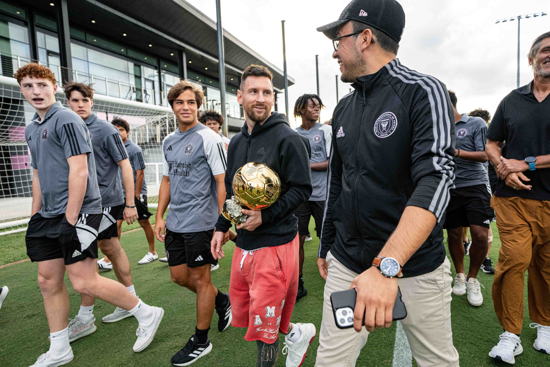Juan Buitron walking alongside Lionel Messi holding the Ballon d'Or